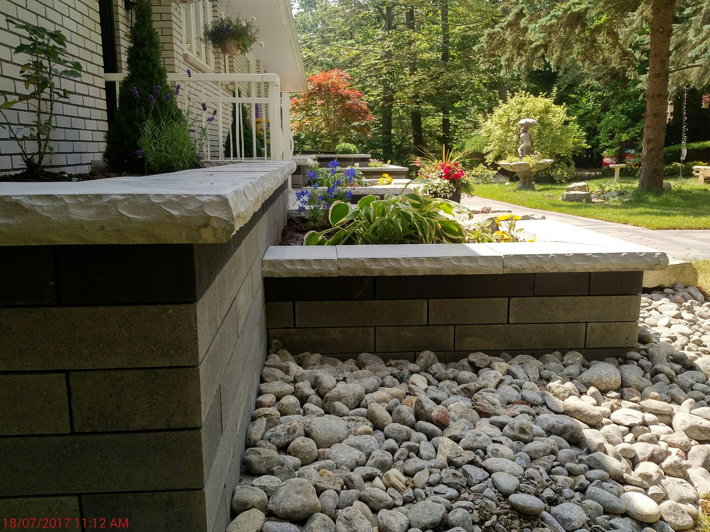 Elegant stone garden path with flowers and statue.