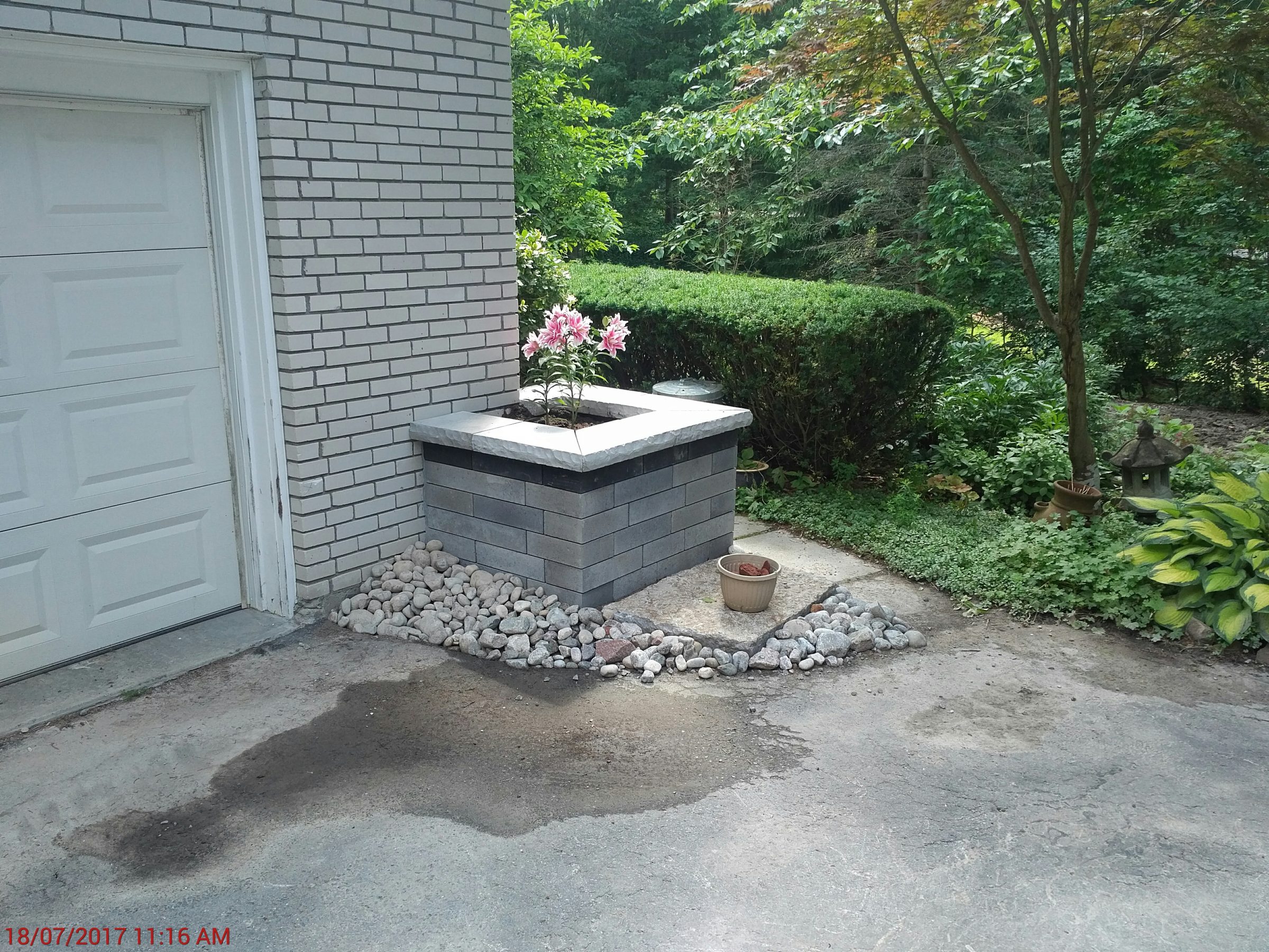 Pink flowers in stone planter by garage