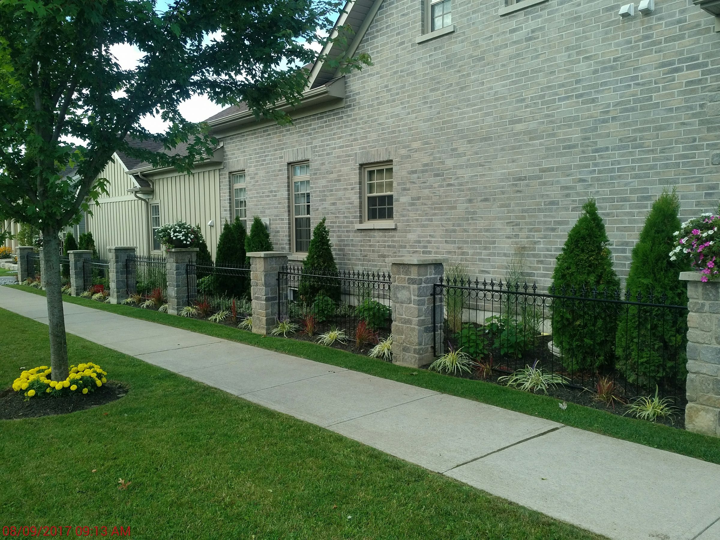 Brick house with garden and sidewalk view.