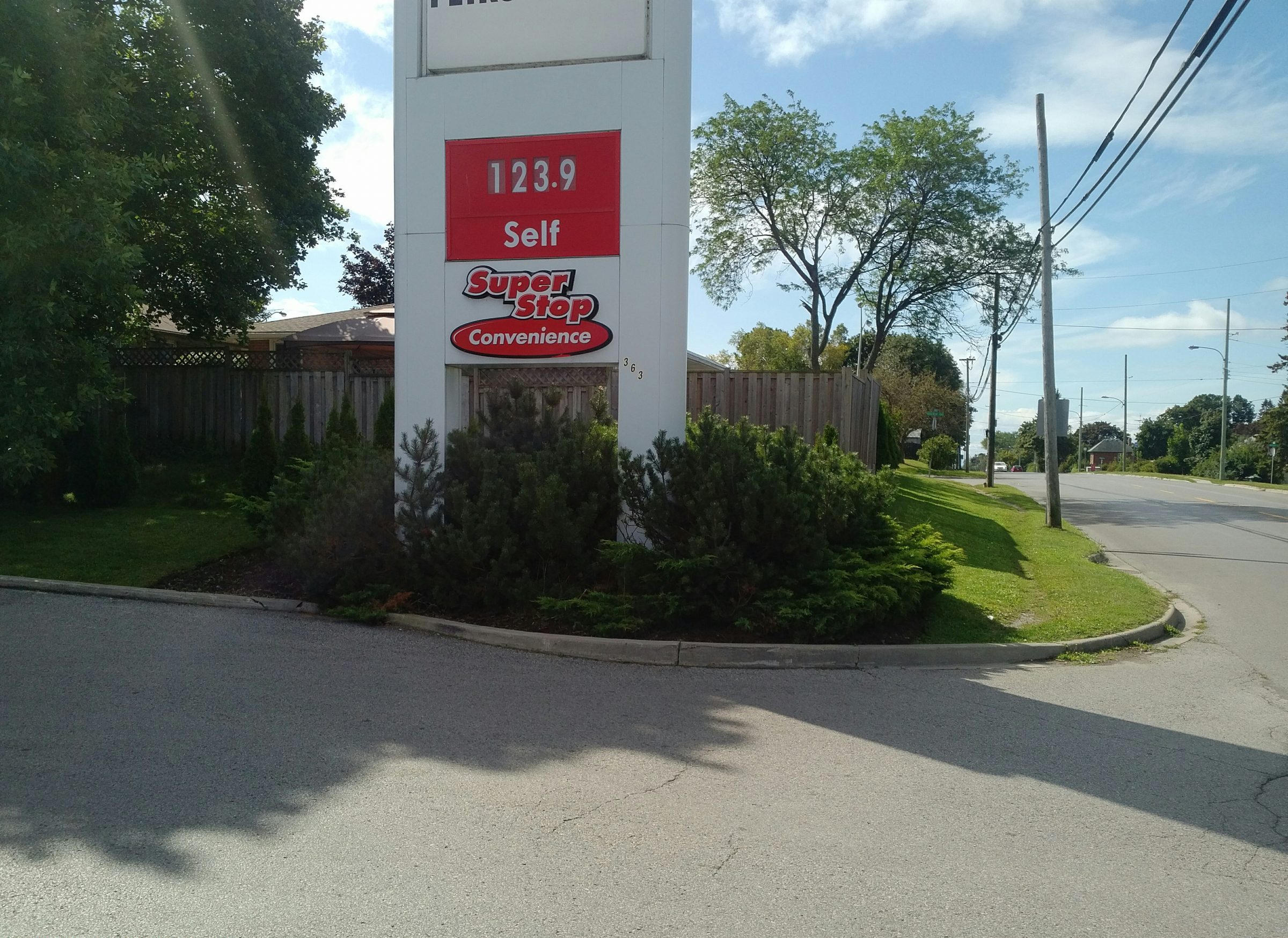 Gas station sign on sunny street corner.