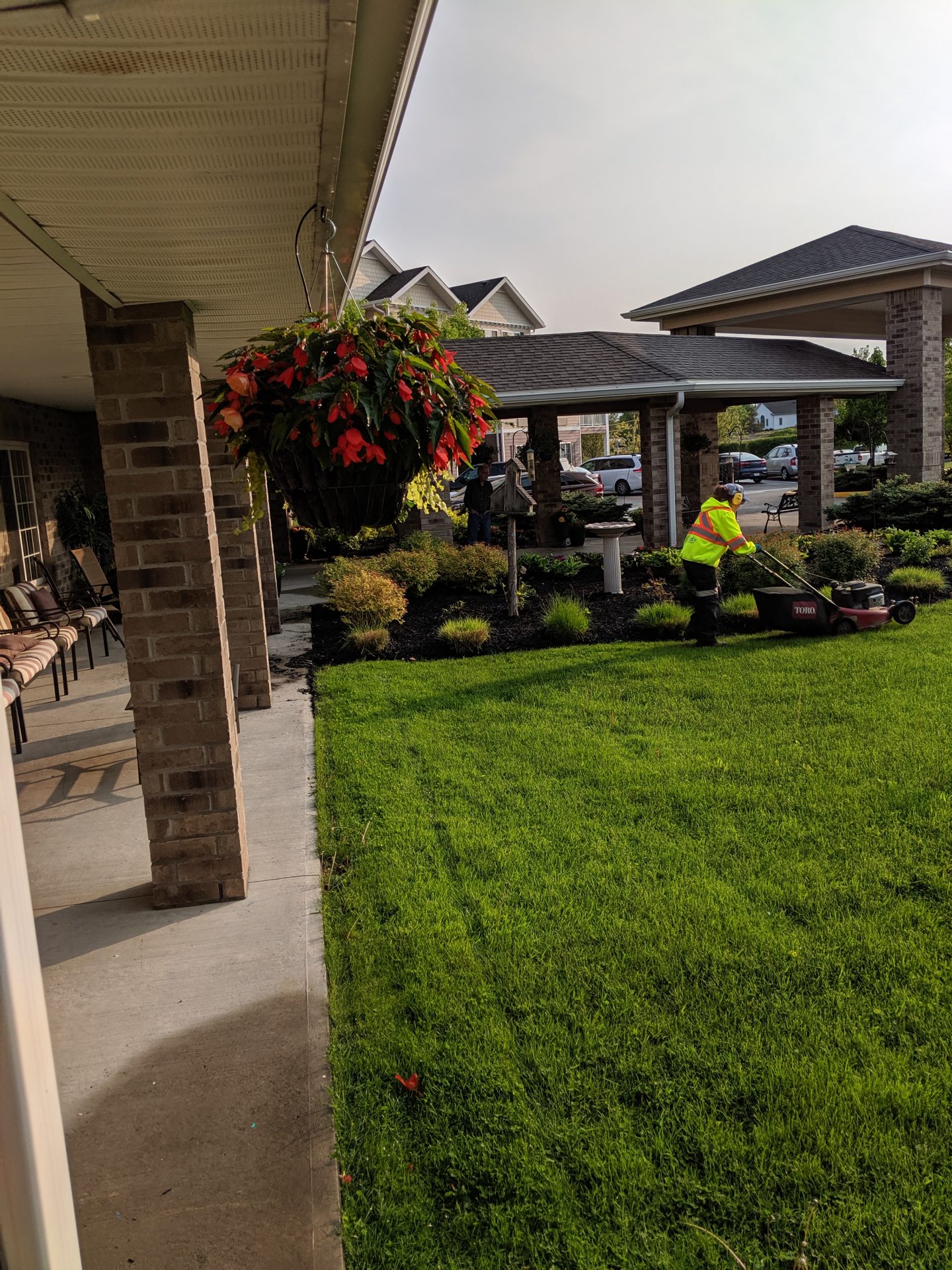 Gardener mowing lawn outside residential building