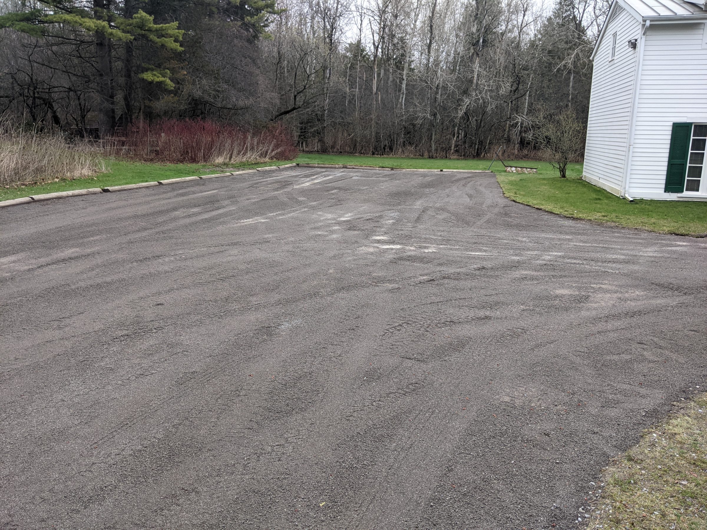 Gravel driveway next to house and trees.