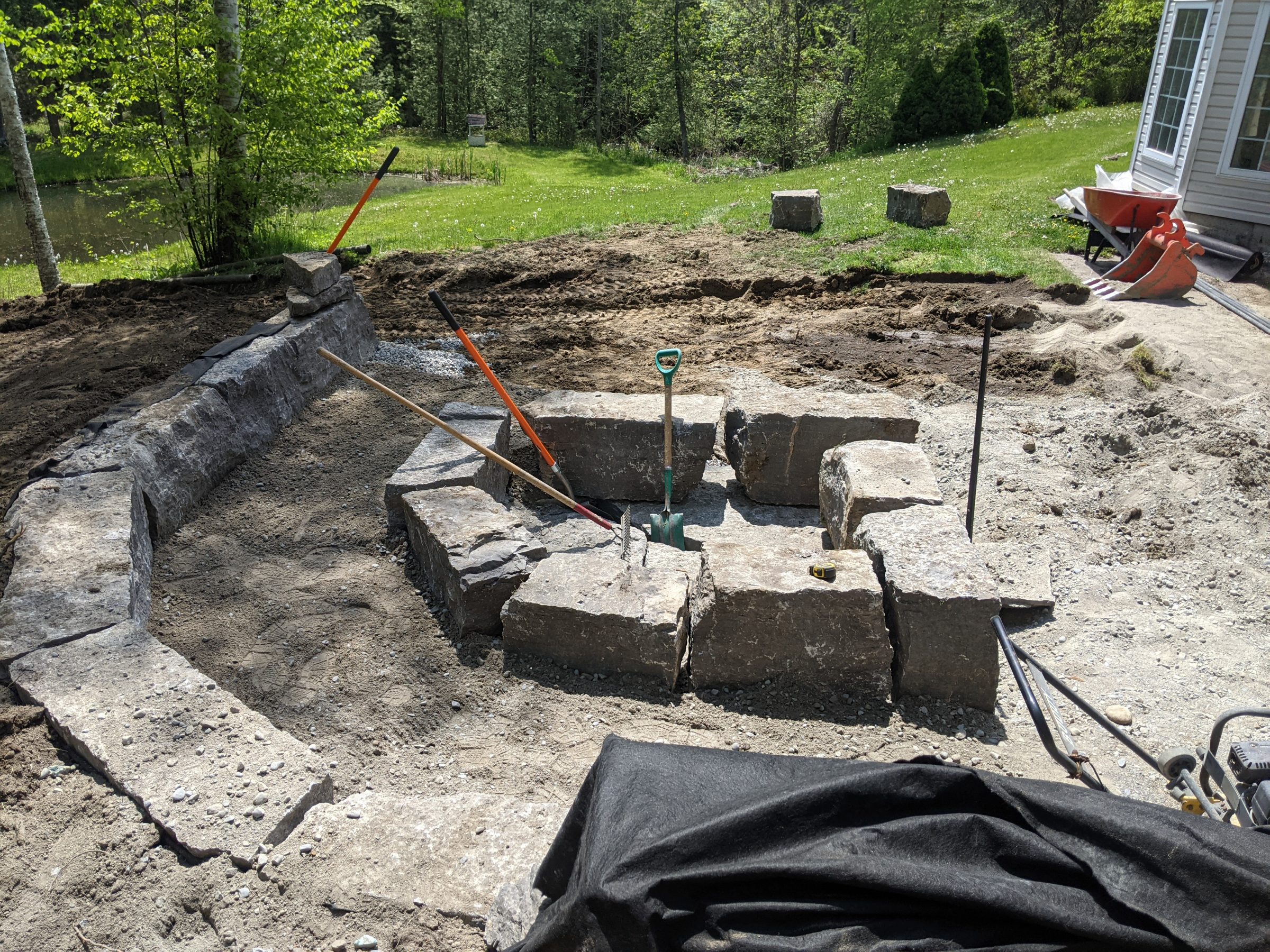 Stone fire pit construction in progress outdoors.
