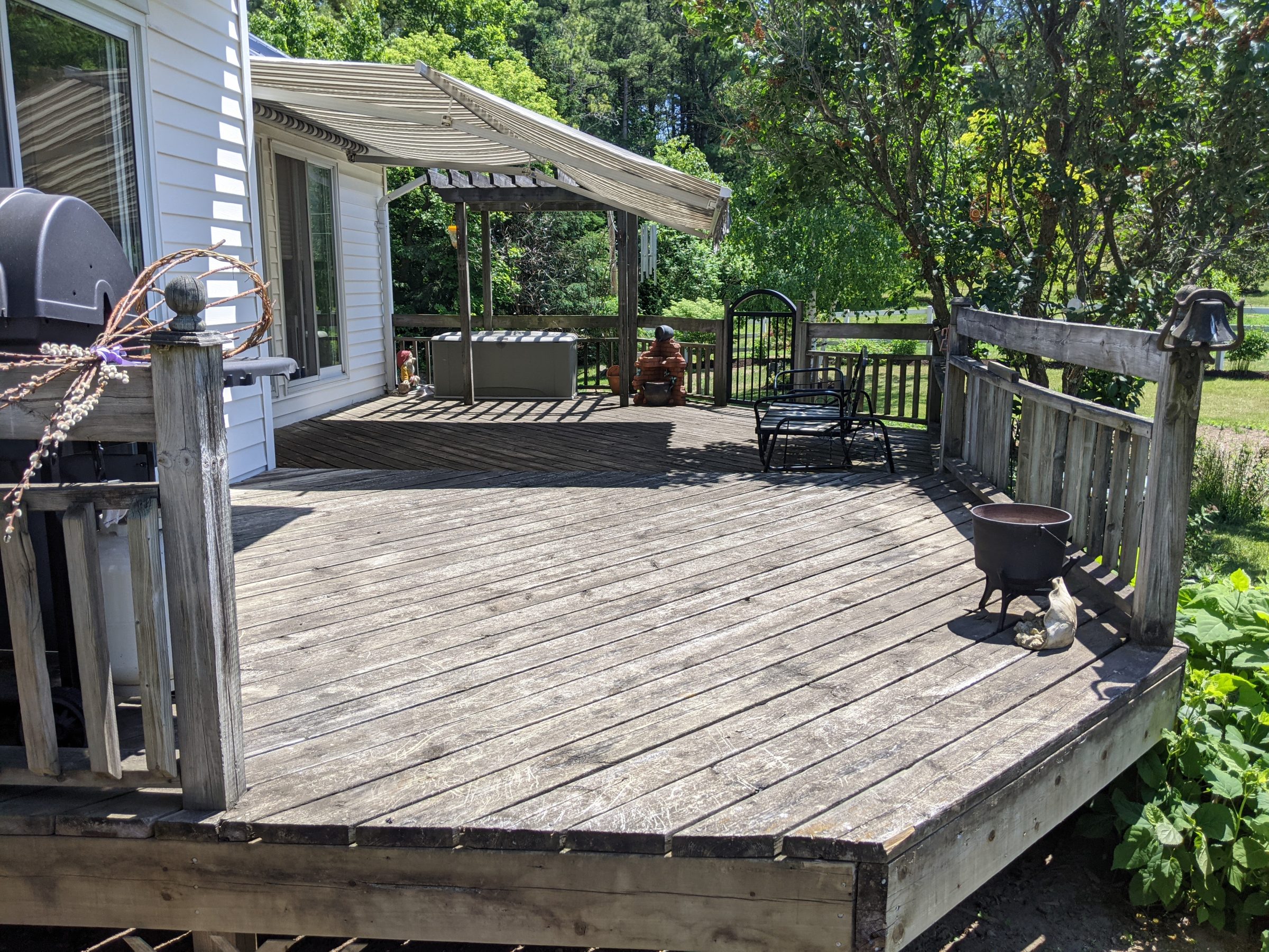 Sunny wooden deck with chairs and green garden view.