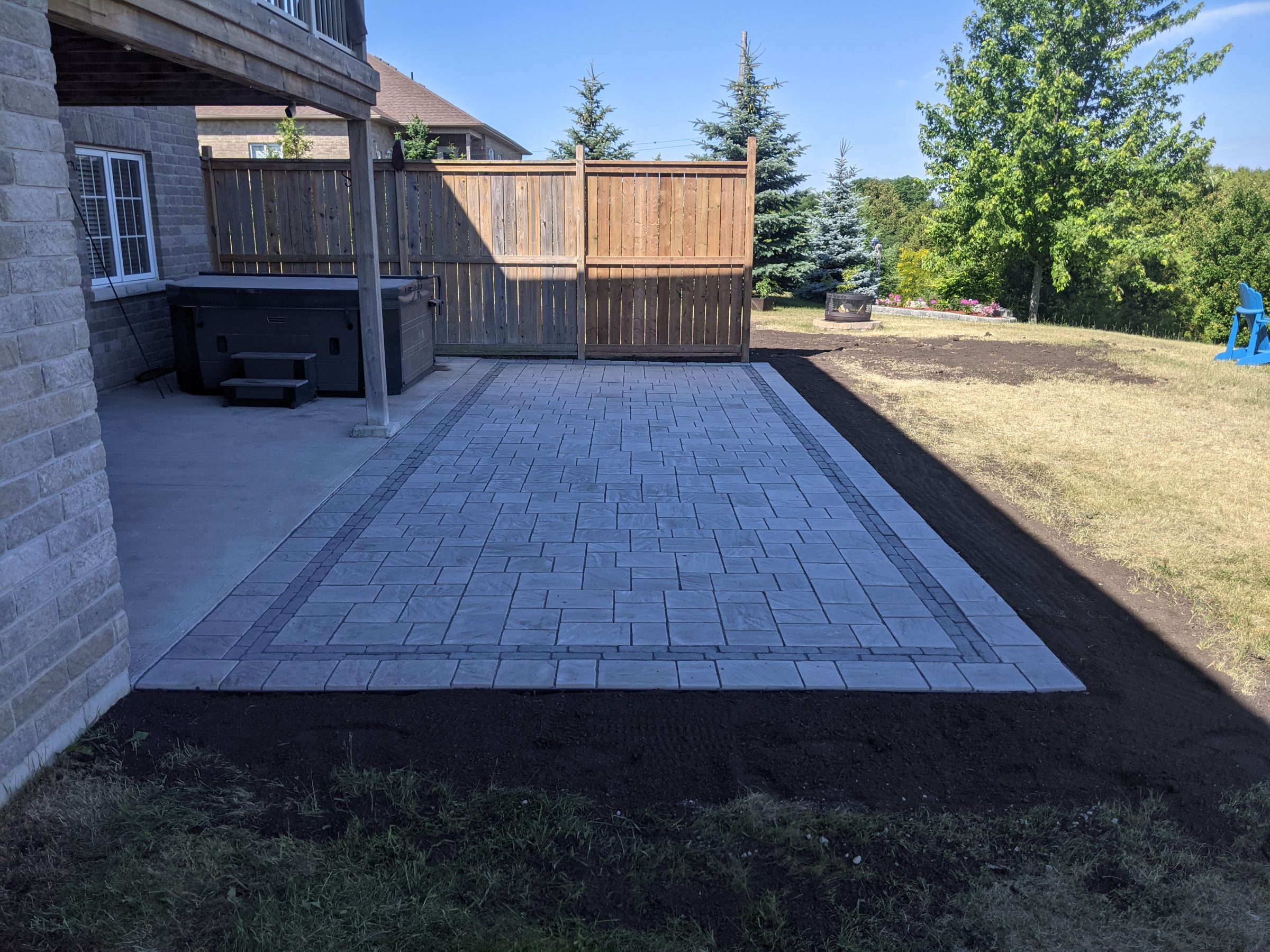 Backyard patio with concrete paving and wooden fence.