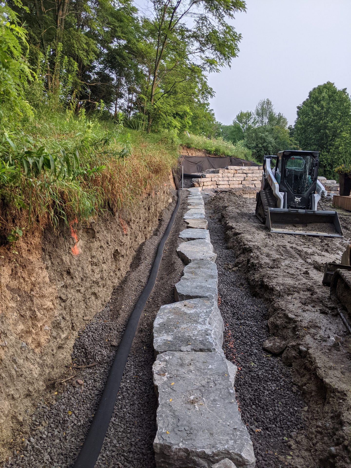 Construction site with excavator and stone retaining wall.