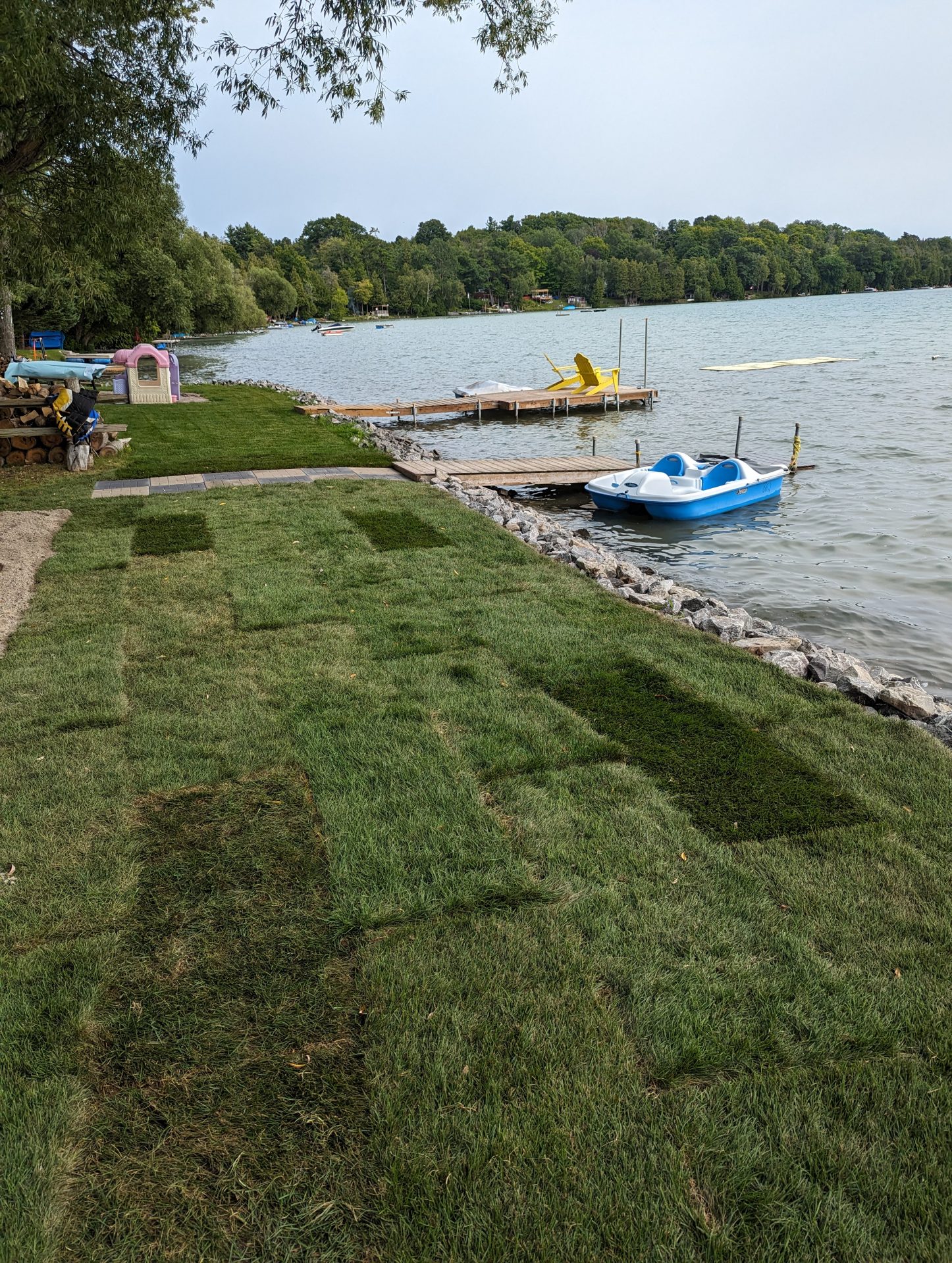 Lakeside lawn with dock and small boats.
