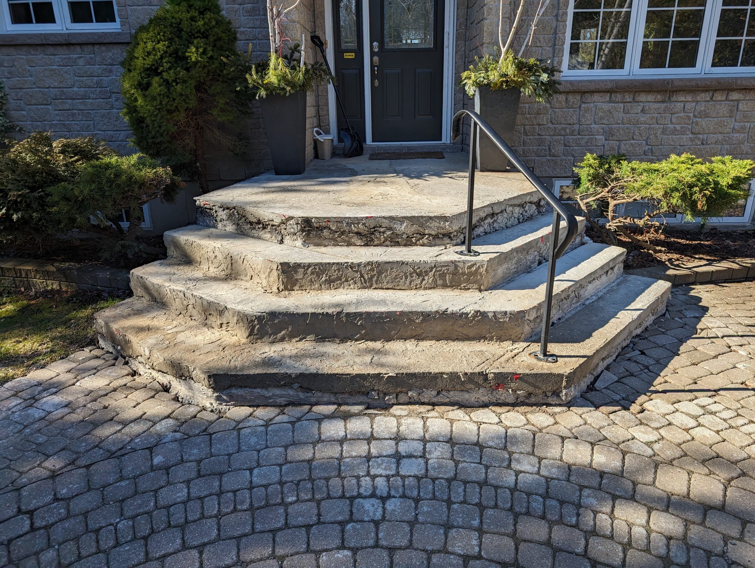 Stone steps with metal handrail leading to door.