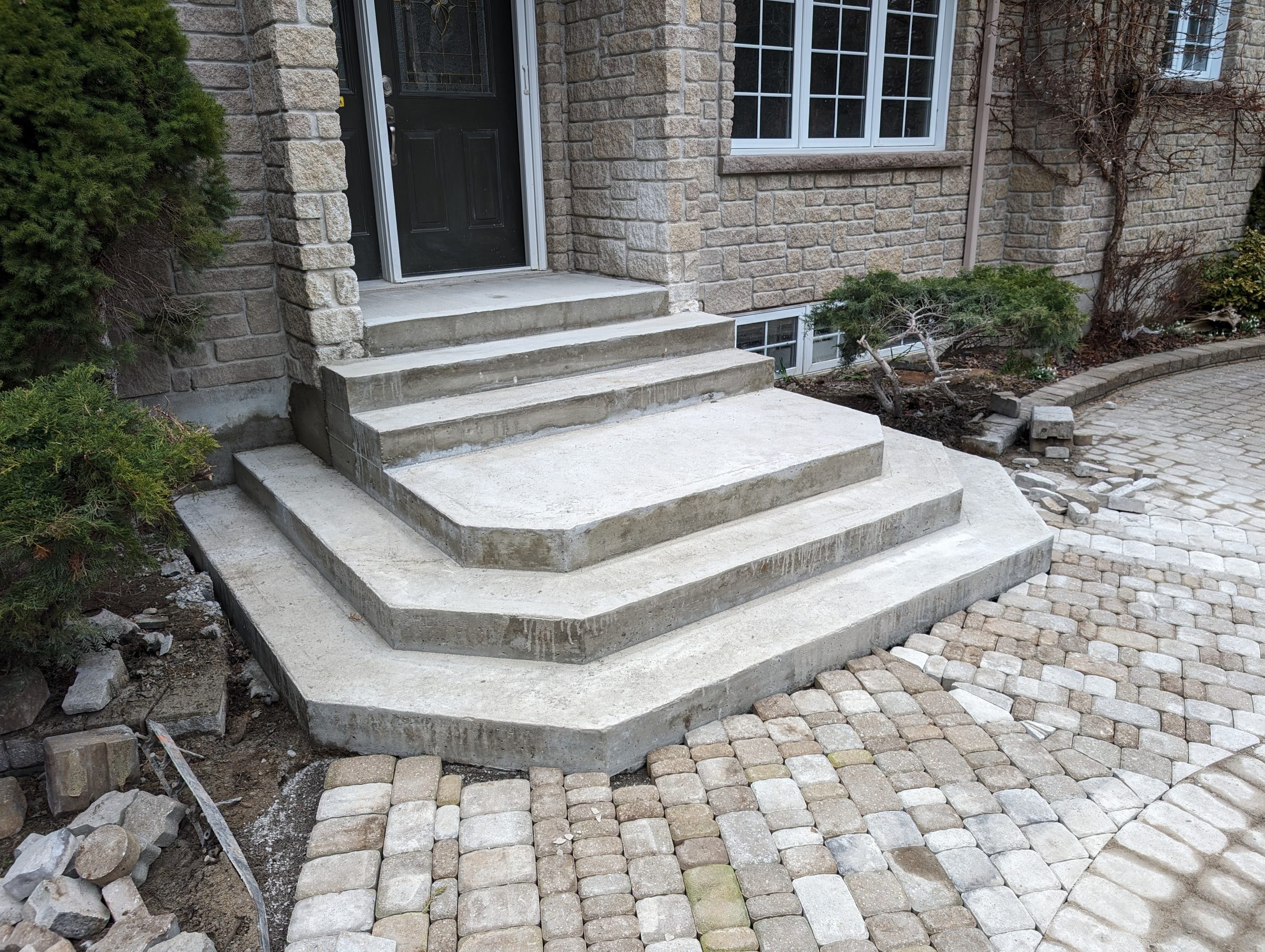 Concrete steps leading to stone house entrance.