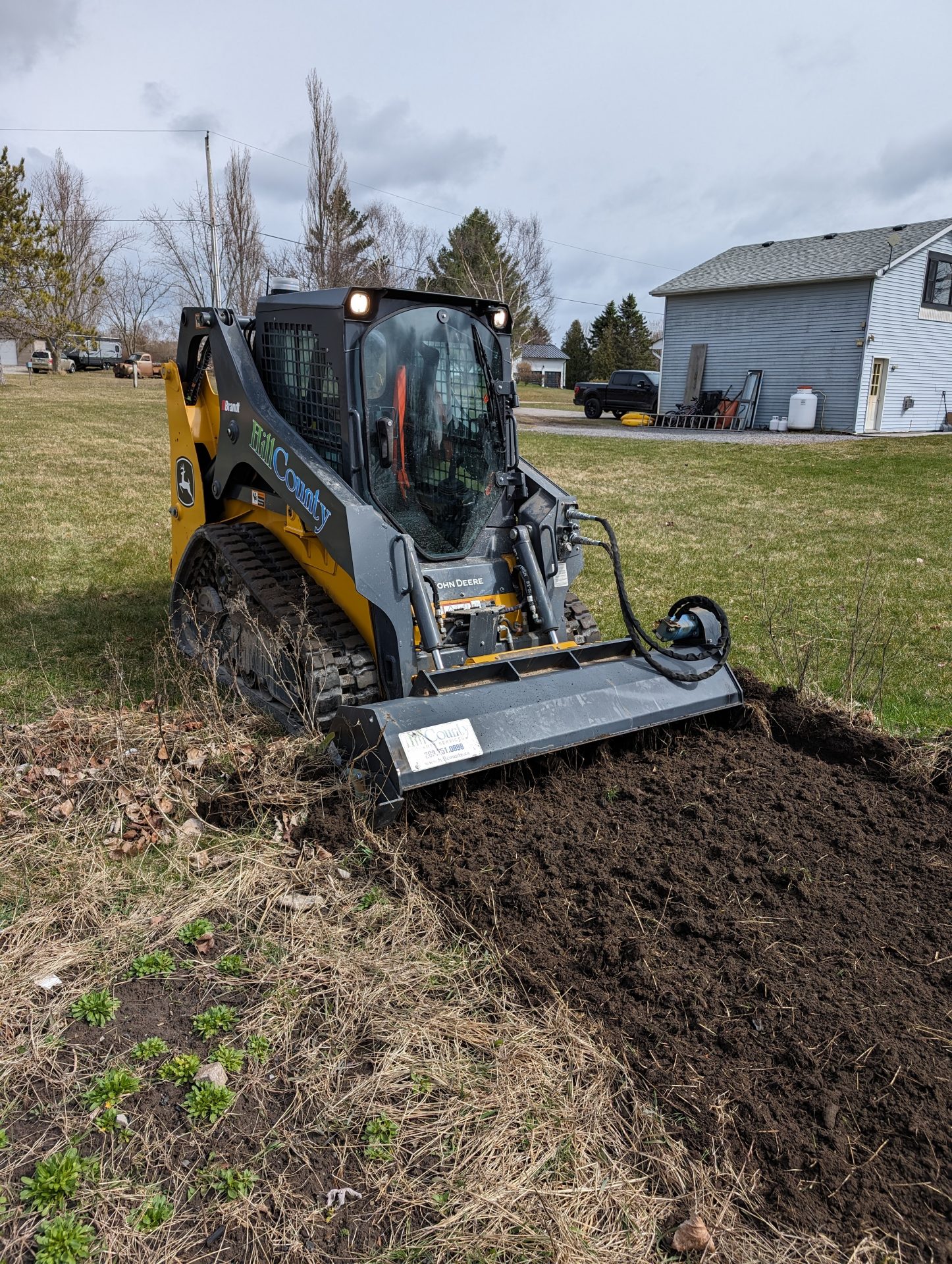 Skid steer tractor tilling a patch of land.