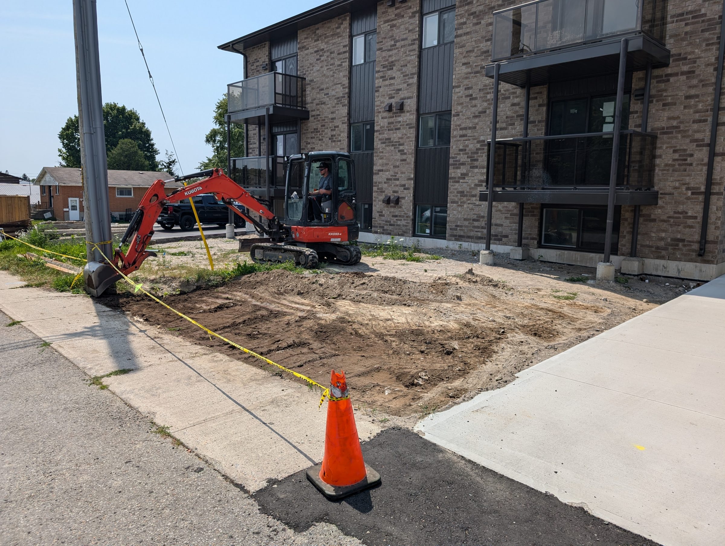 Excavator digging near apartment building construction site.