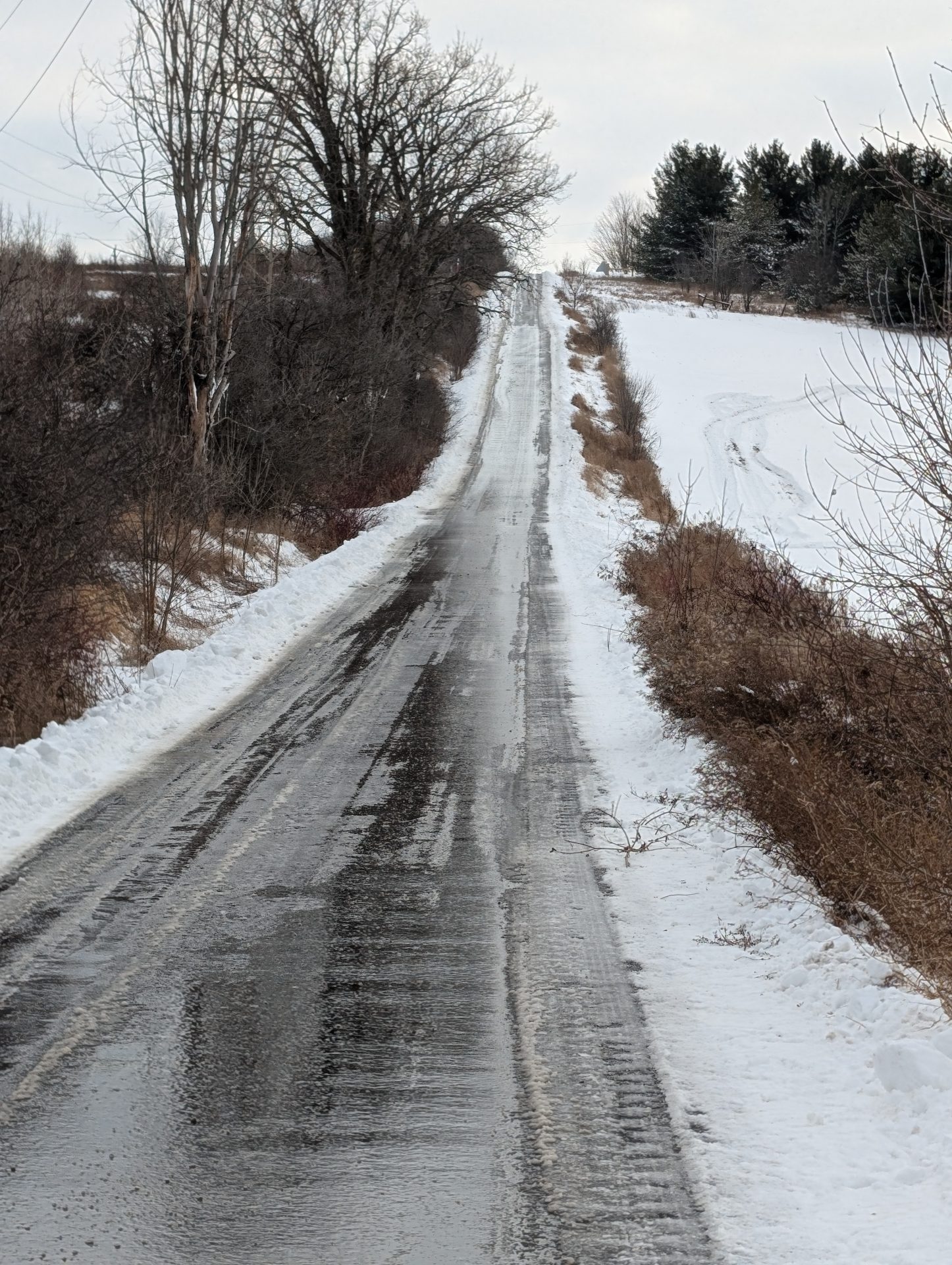 Icy rural road surrounded by snow and trees