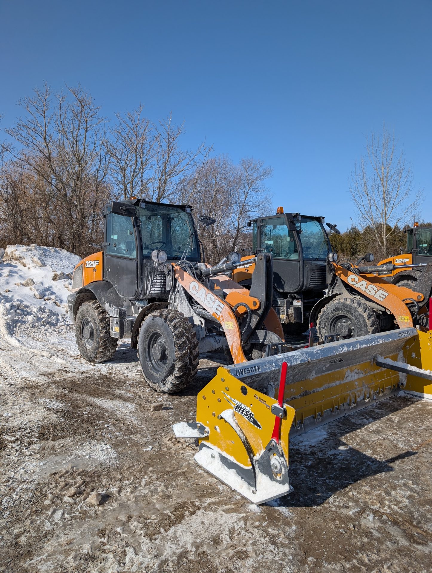 Snow plows and wheel loader in snowy construction site.