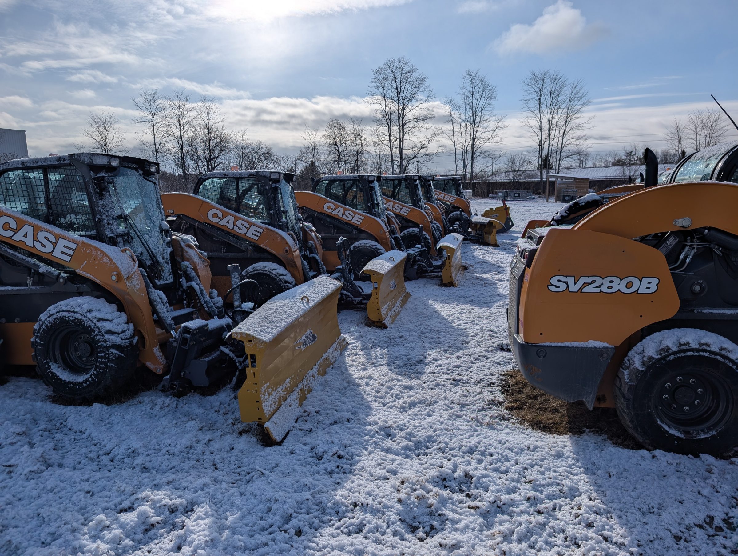 Row of snow-covered construction vehicles in snowy landscape.