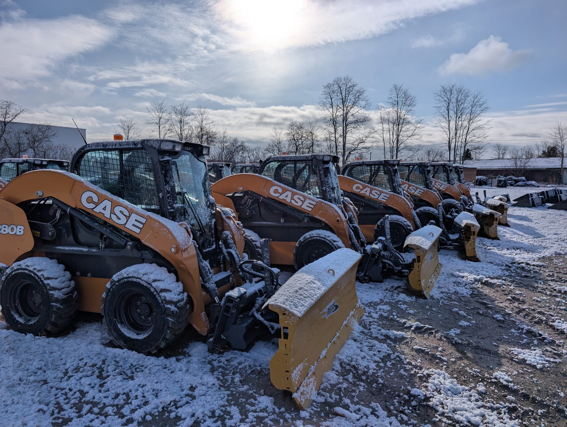 Snow-covered construction vehicles in a line outdoors.