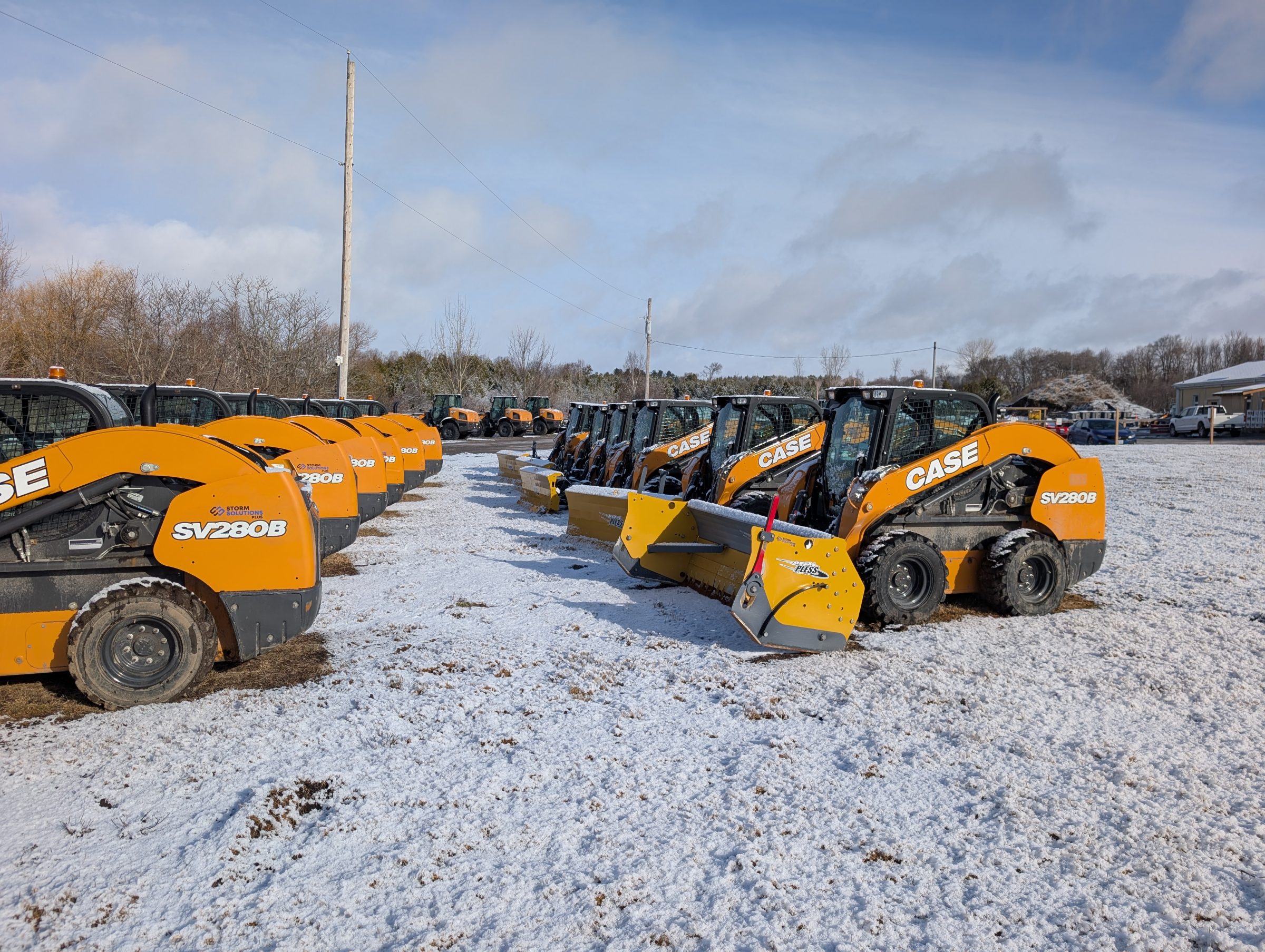 Row of CASE skid steers on snowy ground.