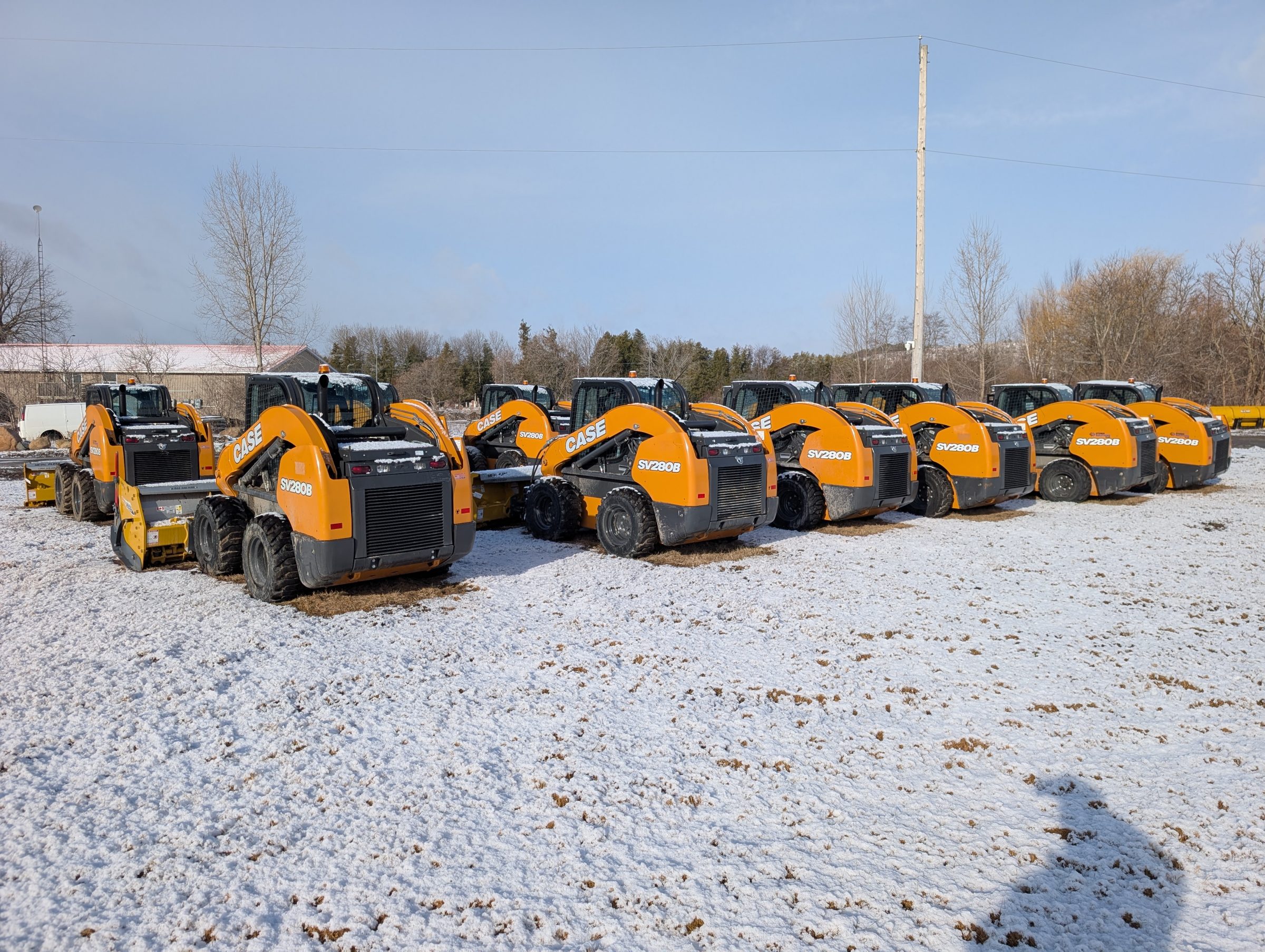 Row of orange CASE construction vehicles in snowy field.