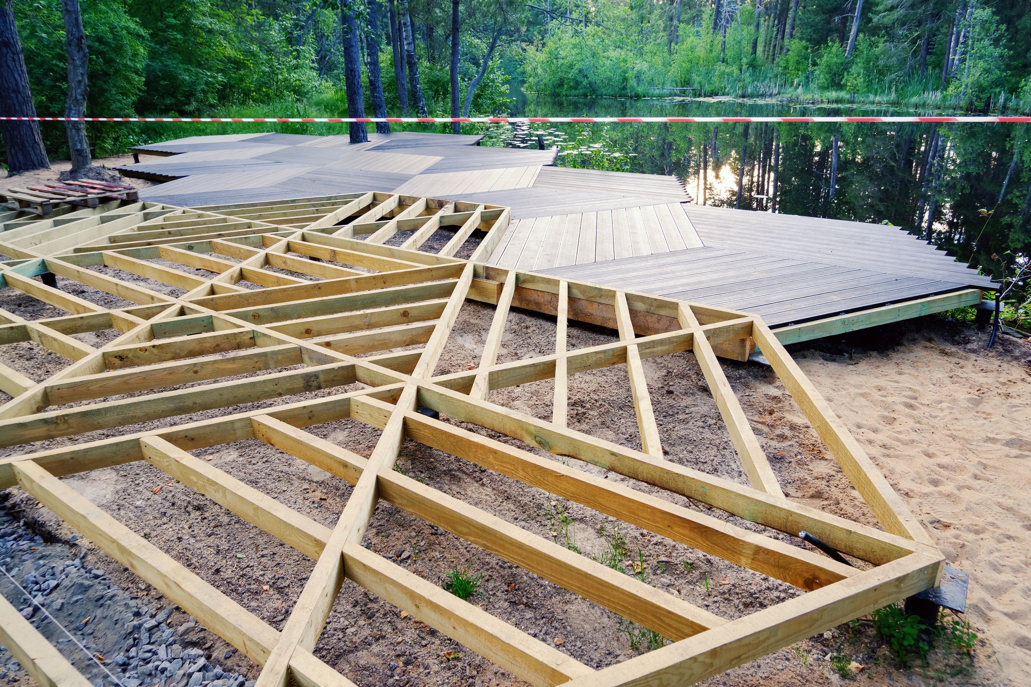Wooden deck construction near forest and lake.