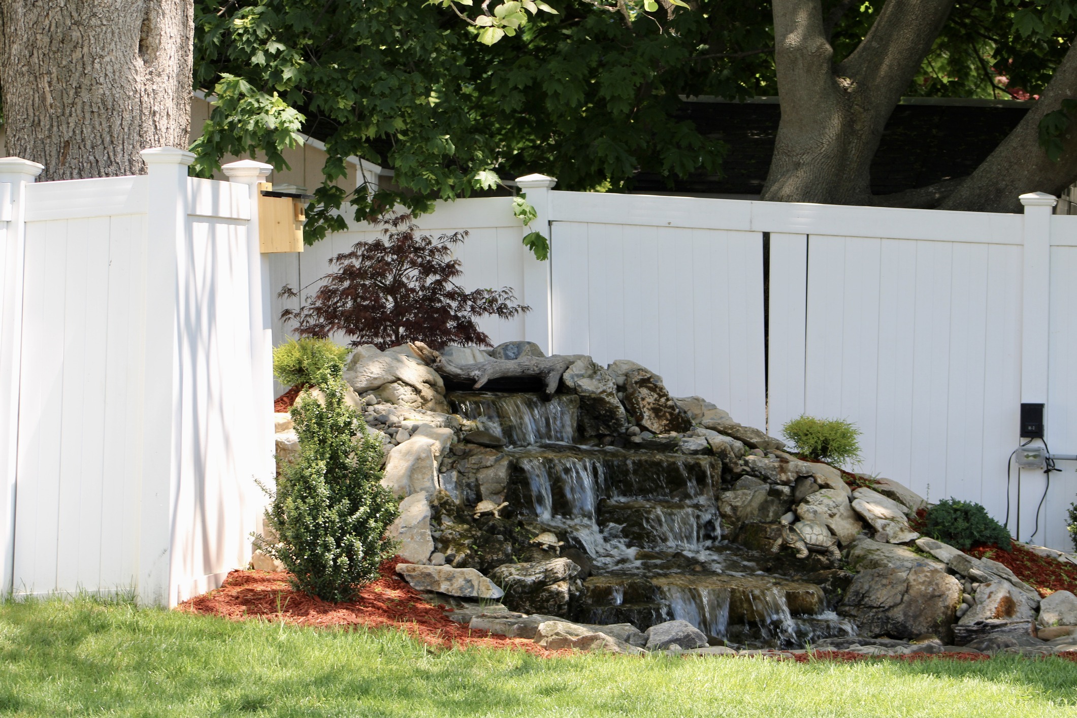 Garden waterfall with white fence background