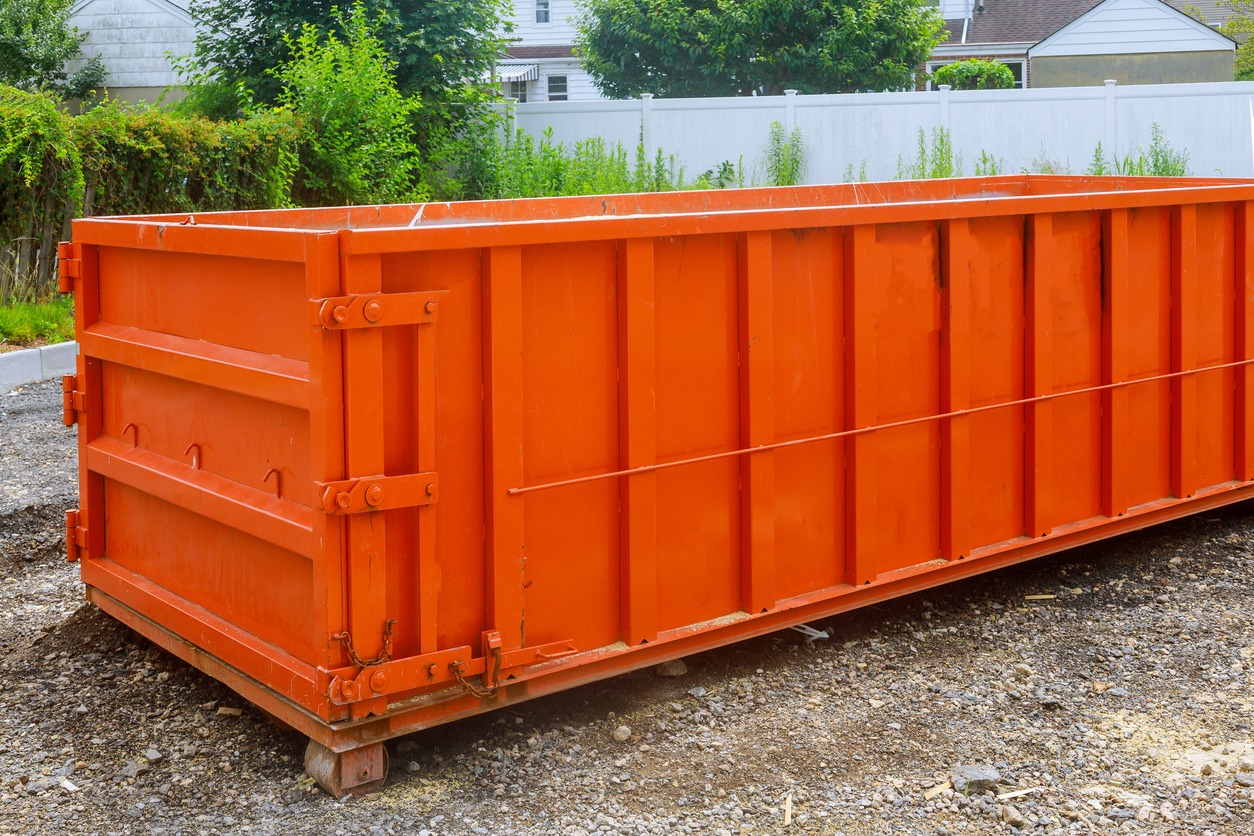 Large orange dumpster on gravel surface