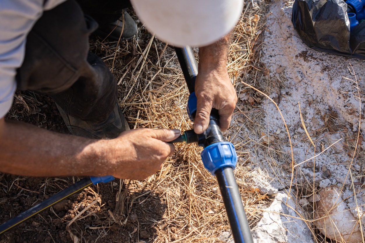 Person assembling irrigation pipe in field