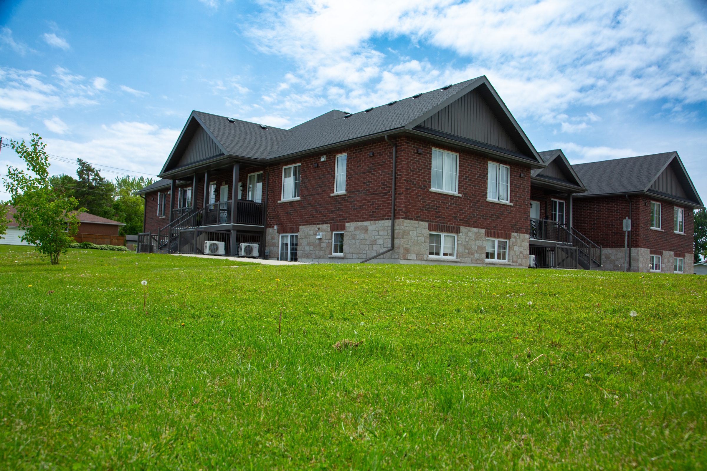 Spacious brick house with green lawn and sky.